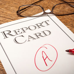 A report card with an "A" and a pair of glasses resting on top of it