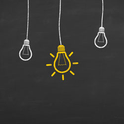 Three light bulbs hanging on a dark background with the middle bulb lit