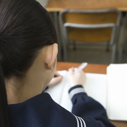 photograph of a girl from behind as she writes in a notebook